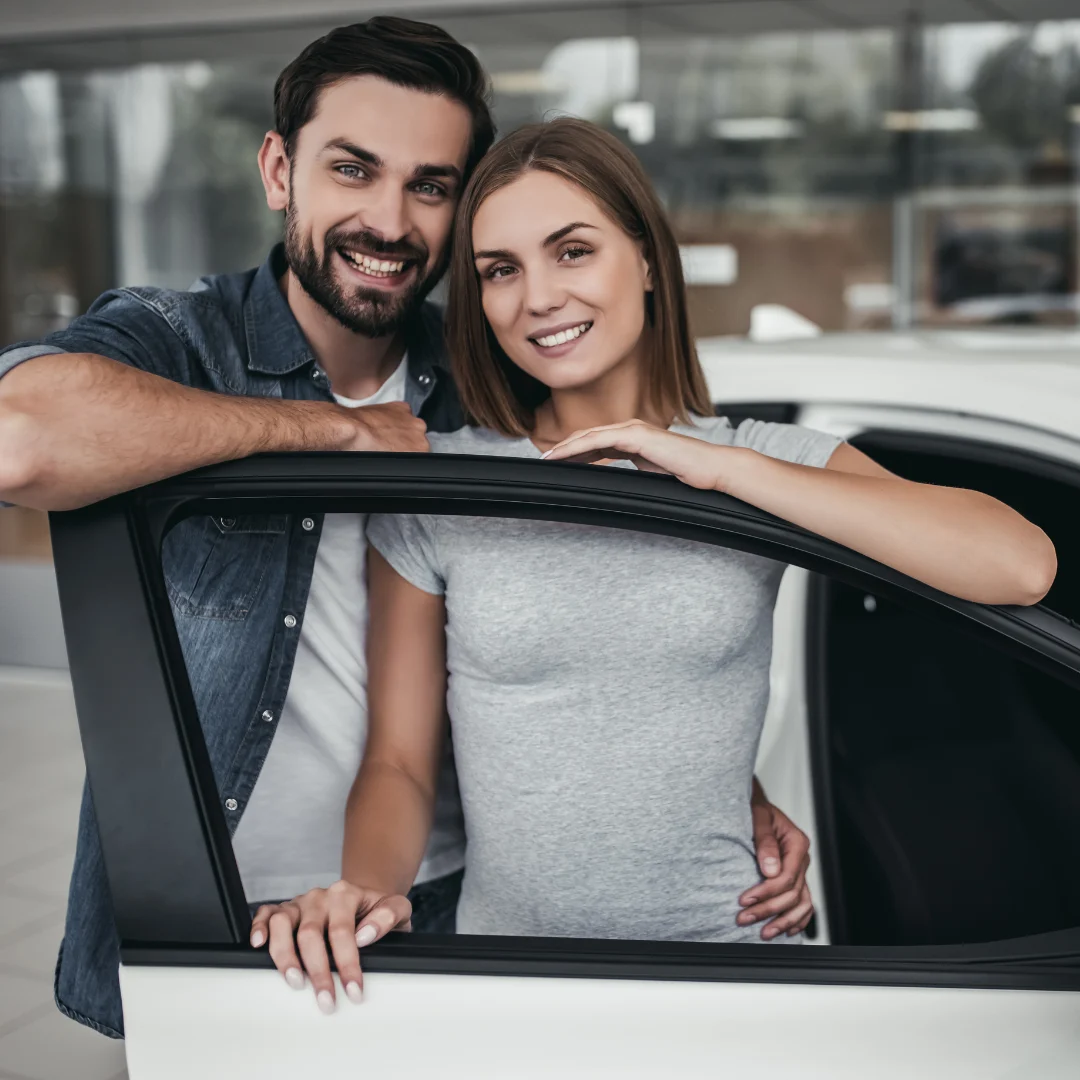 Pärchen lächelnd hinter Autotür