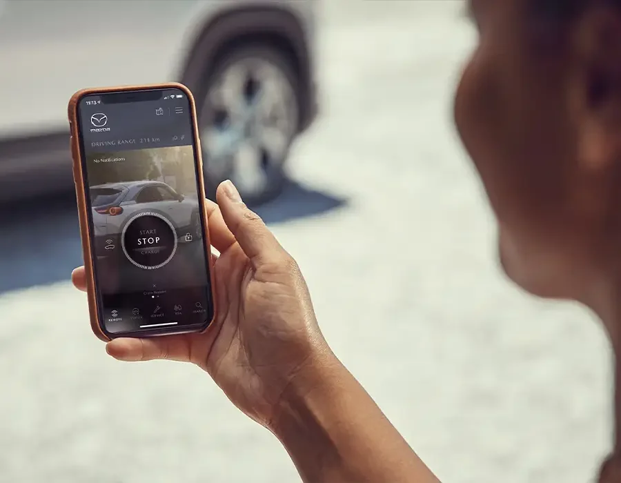 Frau schaut auf die geöffnete Mazda App auf ihrem Smartphone