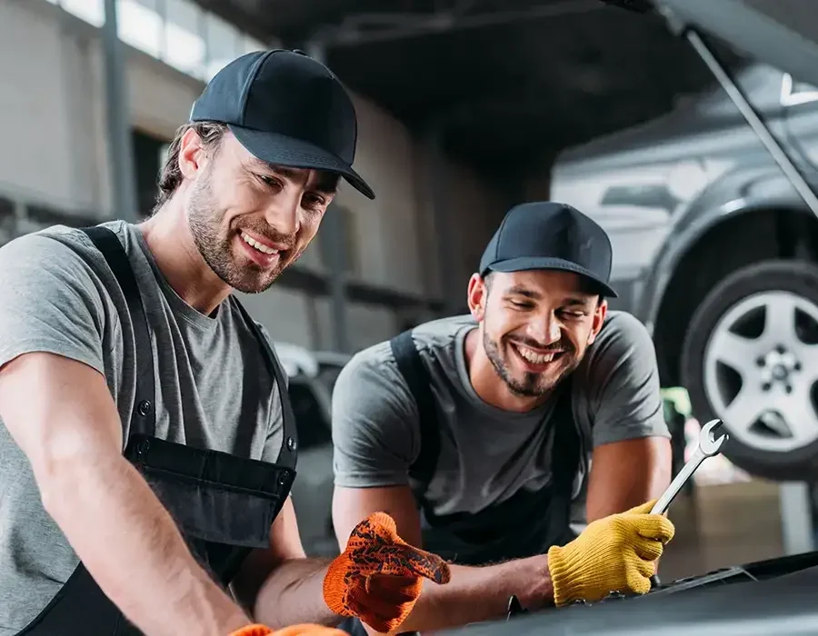 2 Werkstattmitarbeiter mit Werkzeug am Auto